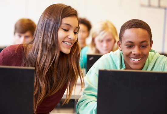 two happy students working together on a laptop