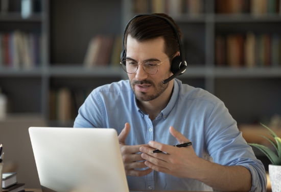 Teacher with a headset working with a student from a laptop