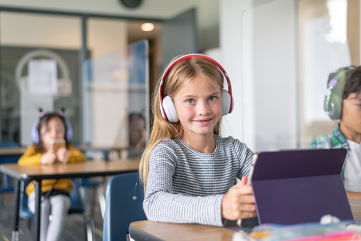 A smiling student sitting in a classroom on a tablet