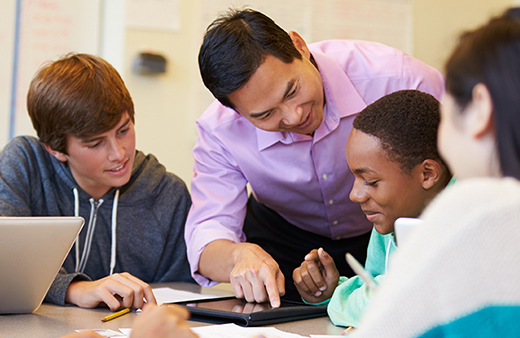 Teacher helping high school students on tablet